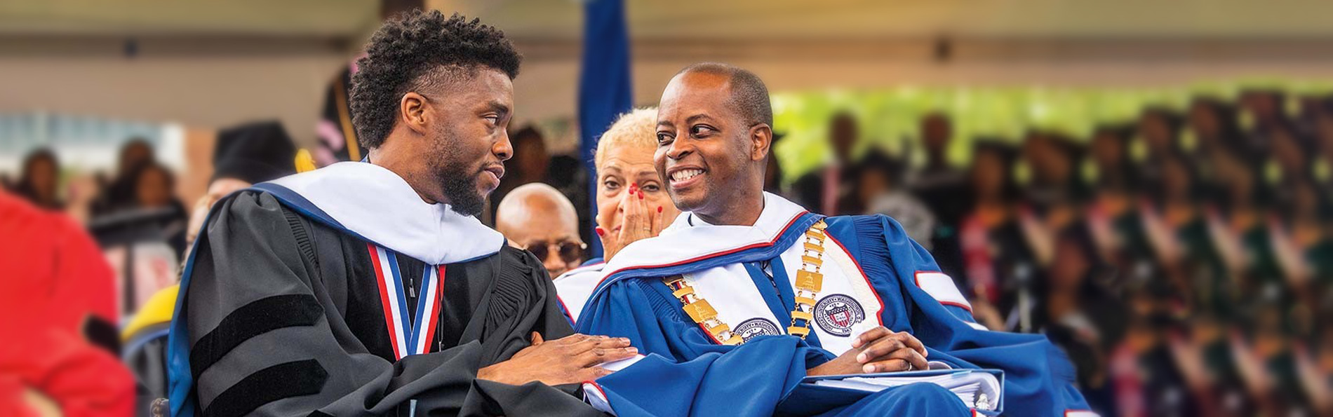 Chadwick Boseman talks to university president in graduation gown
