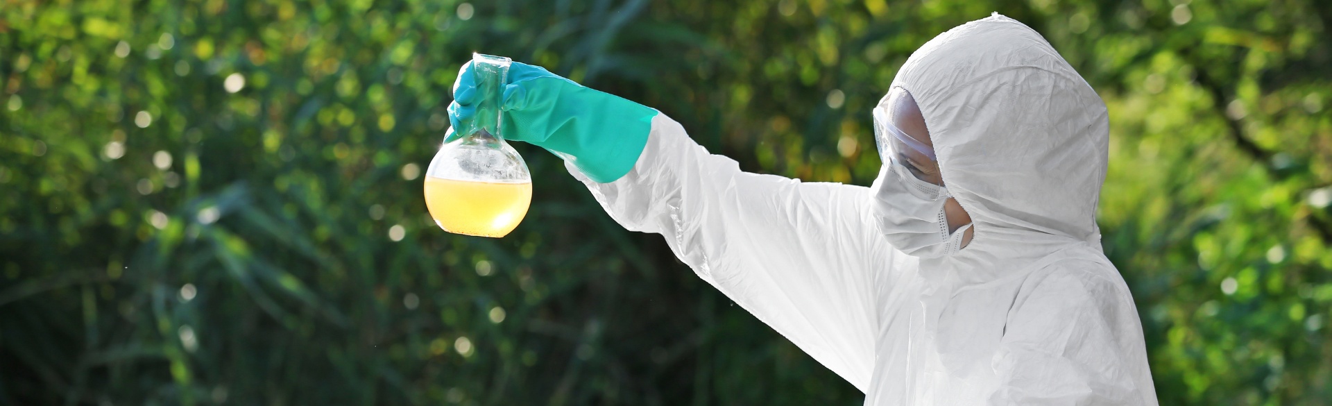 Person wearing protective gear holding contaminated water