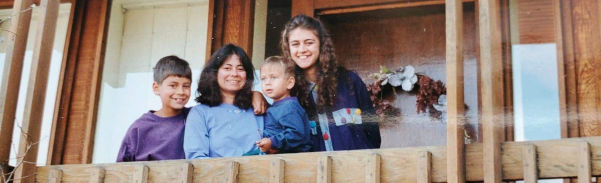 Four people smiling behind wooden railing