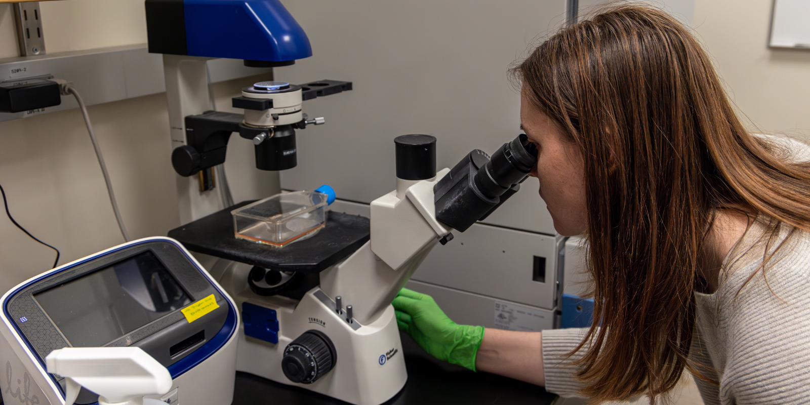 A scientist using a microscope in a lab.