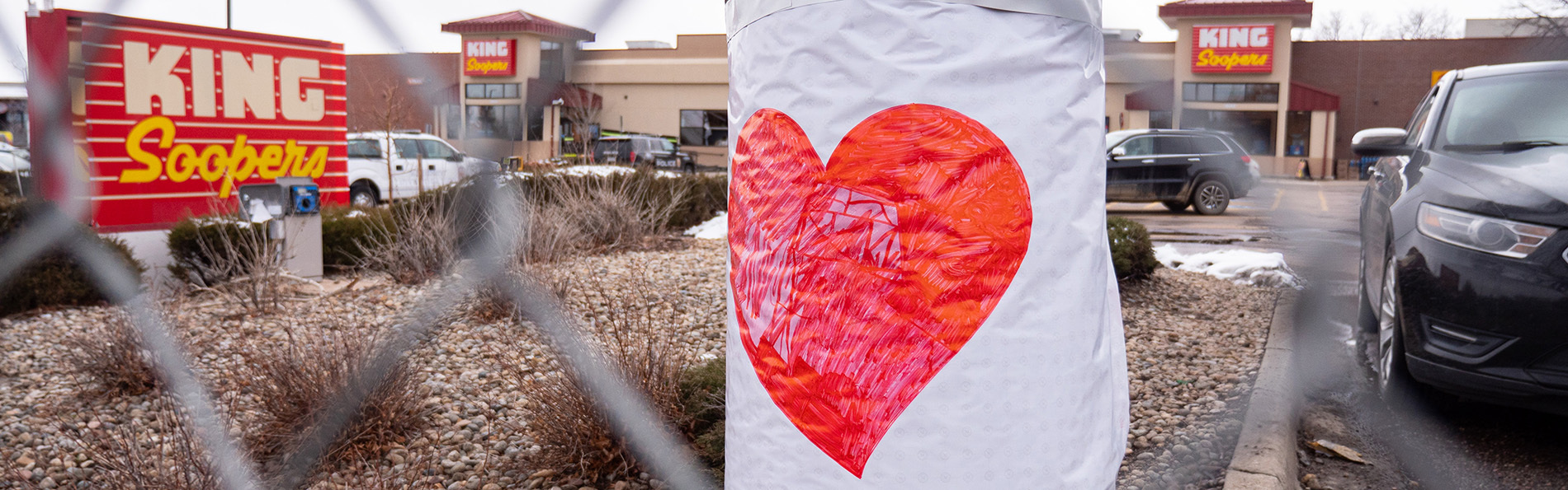 A large poster of a heart on a fence in front of Boulder King Soopers