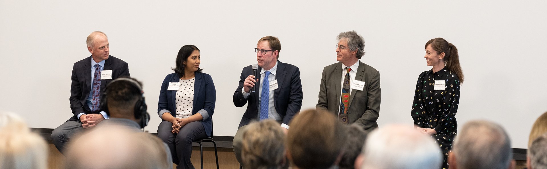 Five panelists line up in chairs